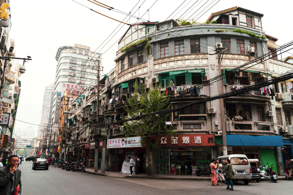 A local street scene in Hongkou district, Shanghai, showcasing traditional shops and everyday life away from typical tourist spots.