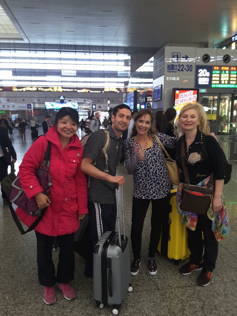 "Tour guide greeting three international travelers with luggage at Shanghai Pudong Airport for a layover tour."